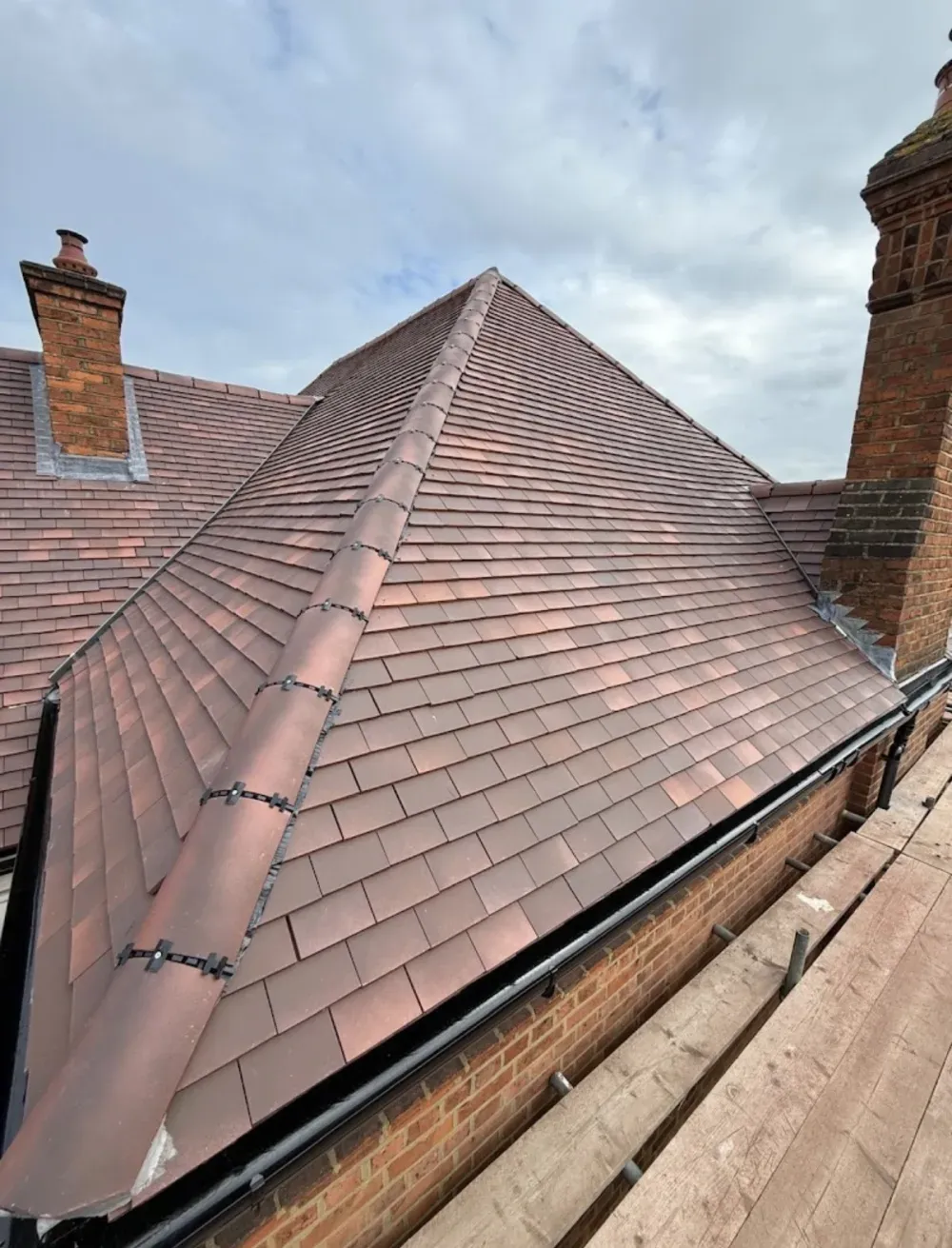 Newly fitted clay tile roof with new black guttering and chimney flashing