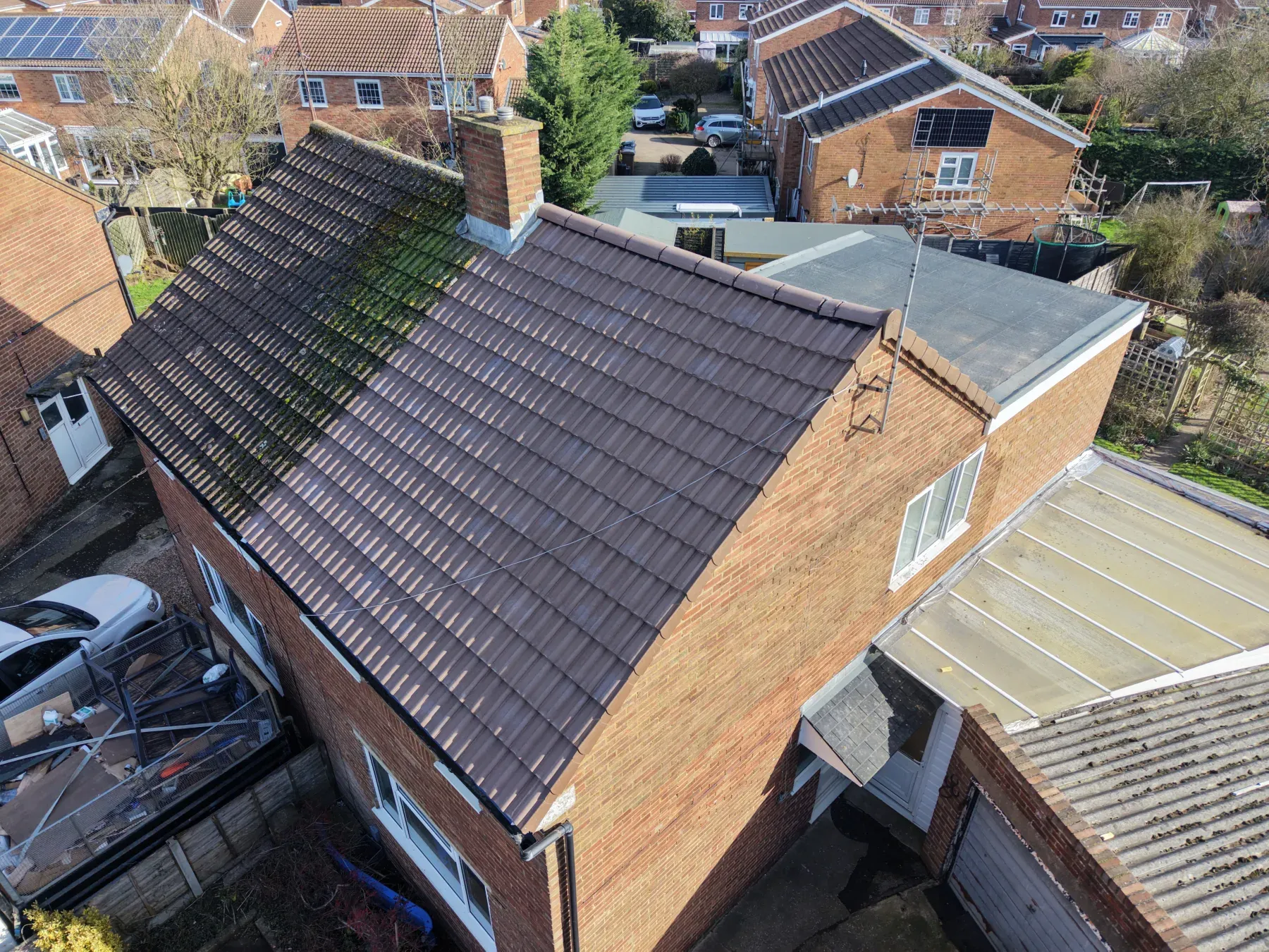 Aerial view of a detached brick house with a newly tiled roof in brown interlocking tiles, completed by Expert Roofing Services